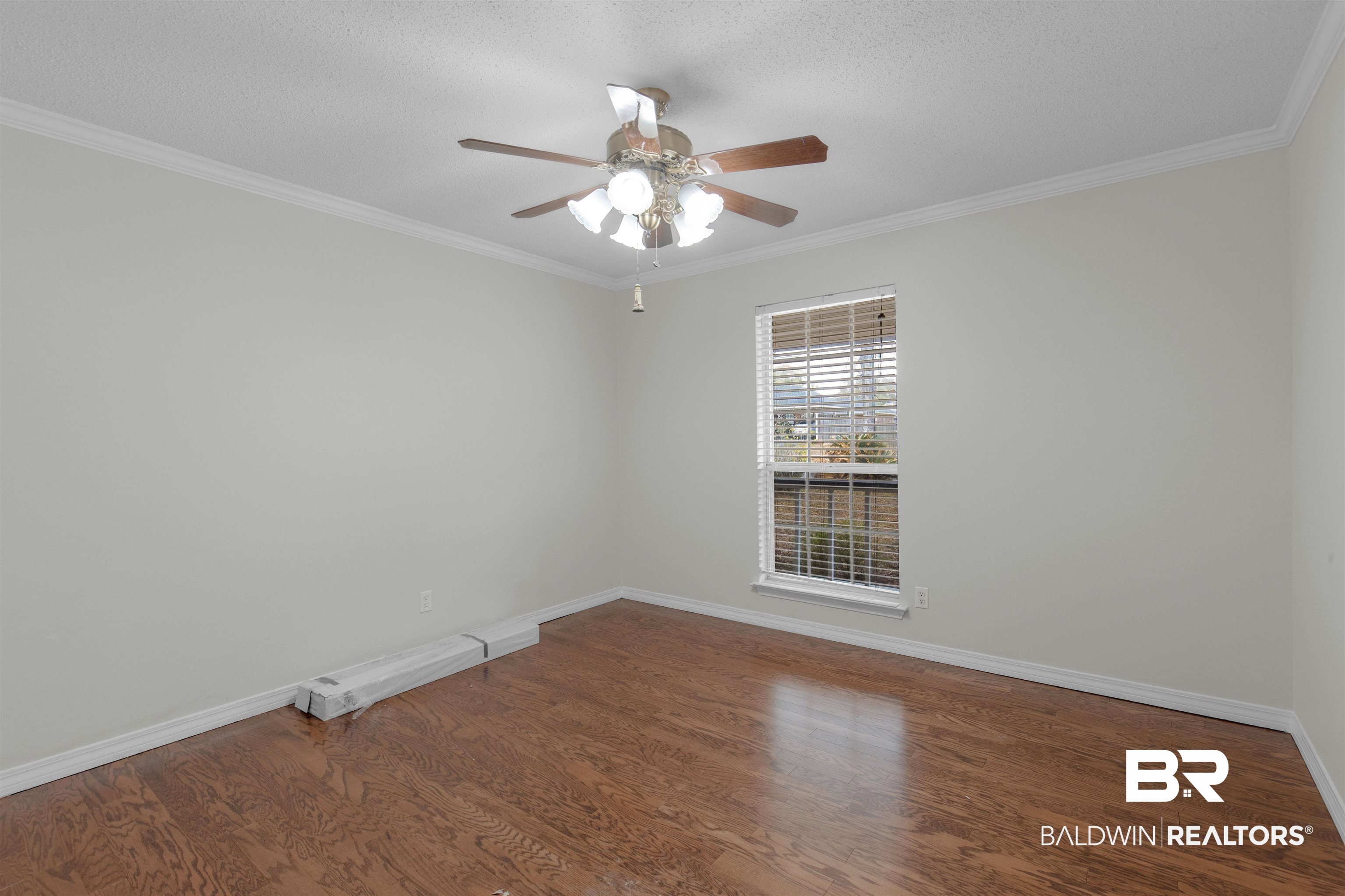 7225 Smithfield Road East Mobile, AL 36695 - Photo 13 of 27 Empty room featuring ceiling fan, baseboards, wood finished floors, and crown molding