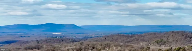 a view of a large mountain range with lush green forest