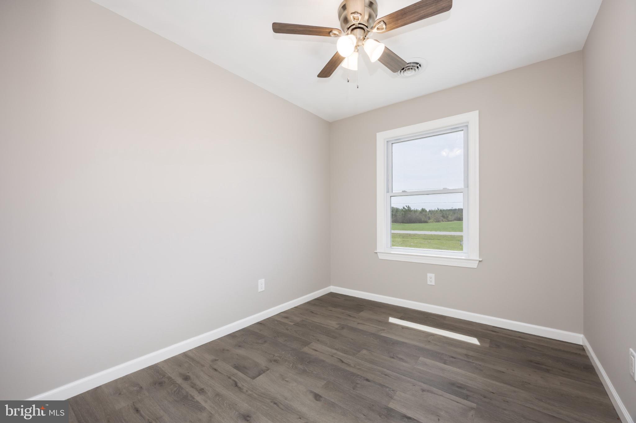 7121 Cedartown Road Snow Hill, MD 21863 - Photo 22 of 52 an empty room with wooden floor chandelier fan and windows