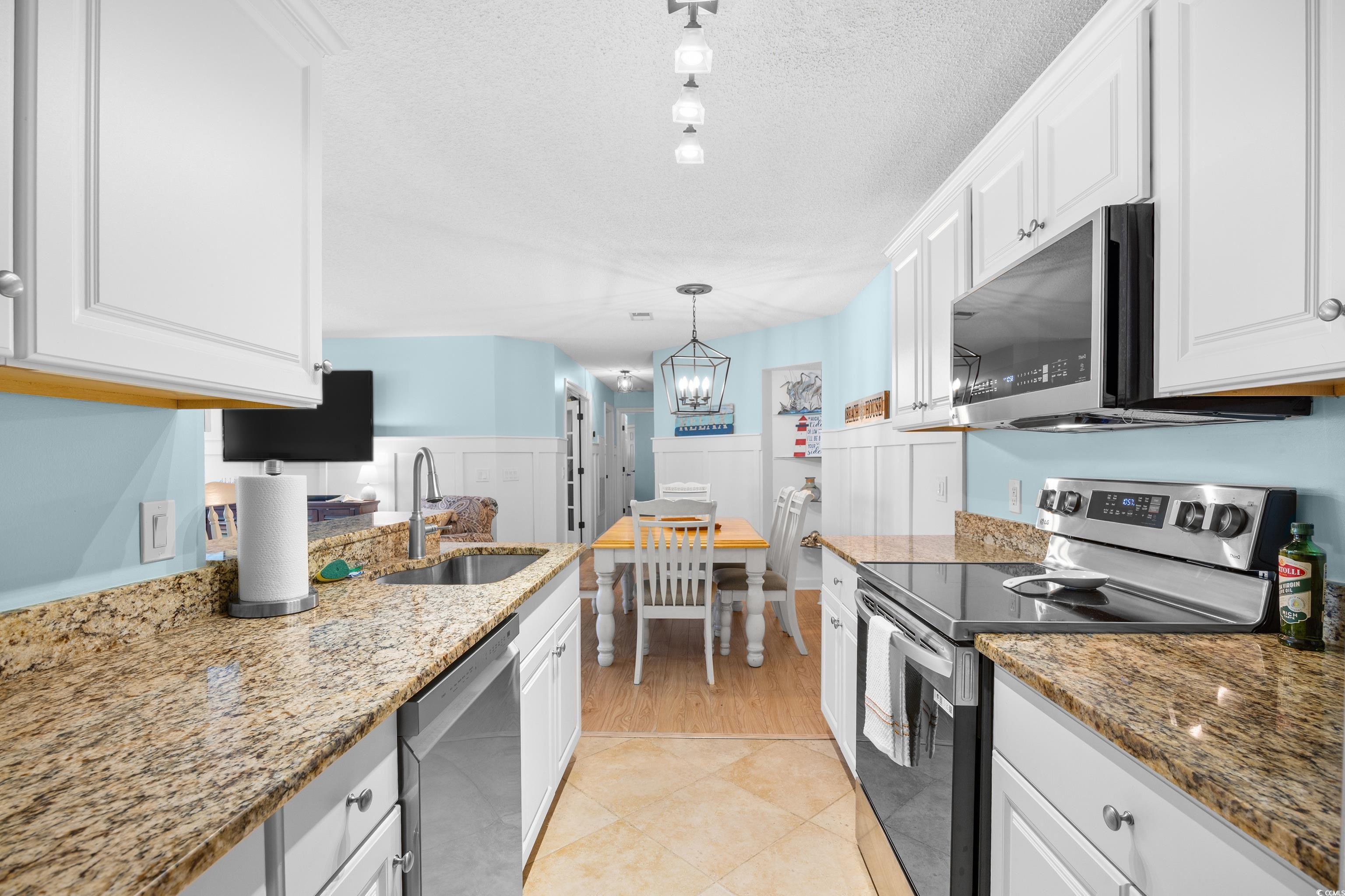 4277 Santolina Way, Unit D Murrells Inlet, SC 29576 - Photo 13 of 40 Kitchen featuring appliances with stainless steel finishes, white cabinetry, light stone countertops, hanging light fixtures, and a textured ceiling