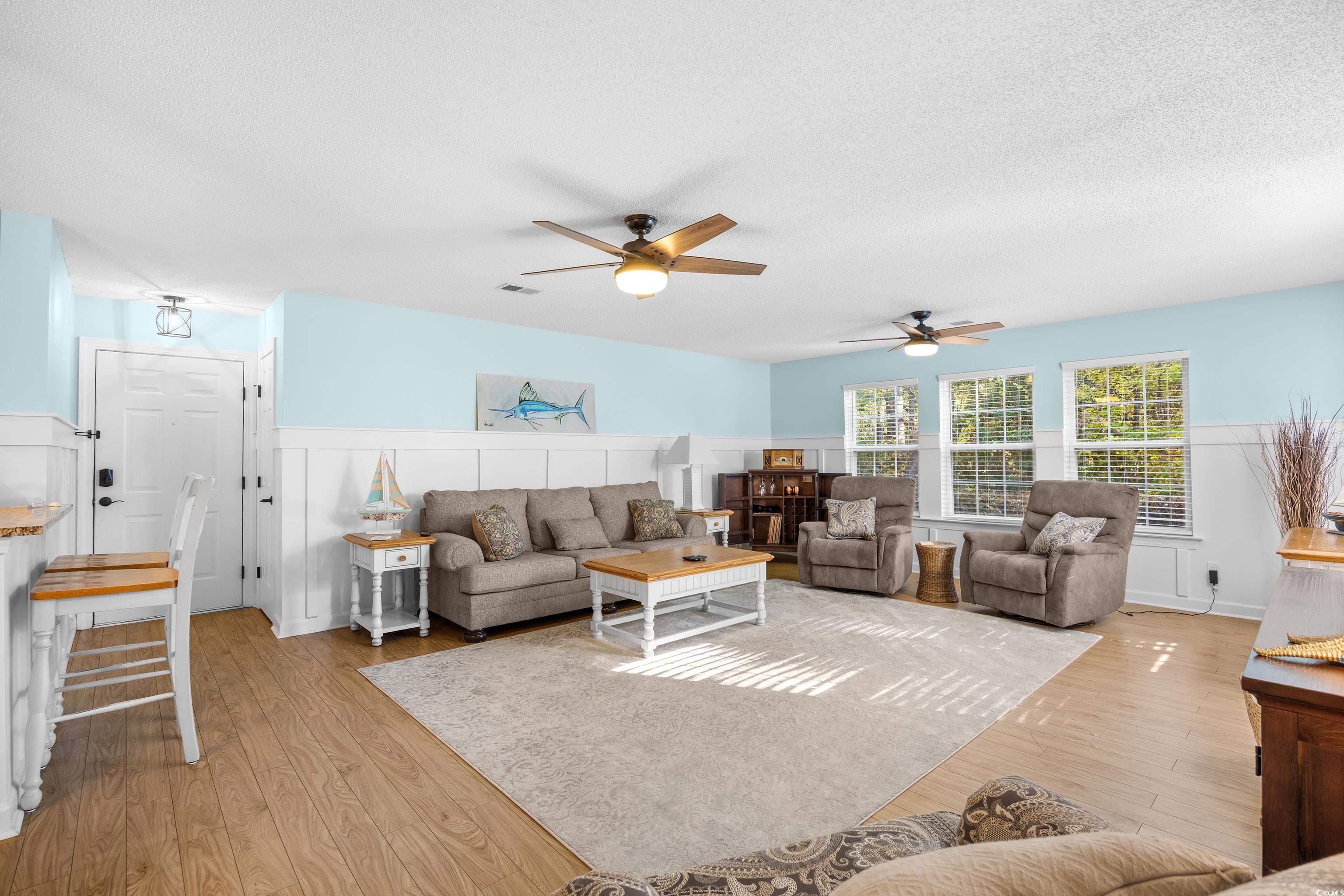 4277 Santolina Way, Unit D Murrells Inlet, SC 29576 - Photo 3 of 40 Living area with wainscoting, ceiling fan, light wood-type flooring, a textured ceiling, and a decorative wall