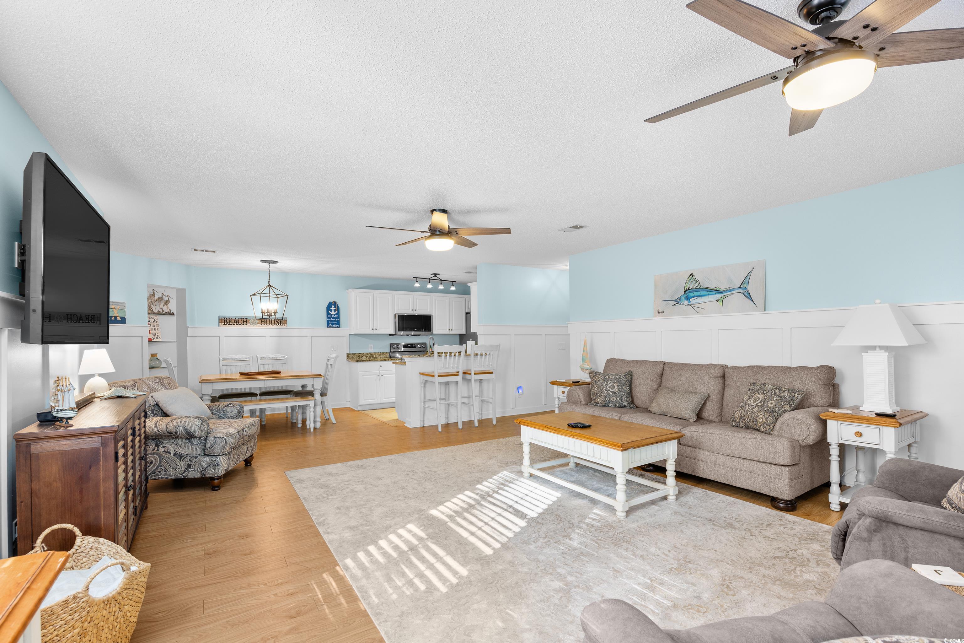4277 Santolina Way, Unit D Murrells Inlet, SC 29576 - Photo 4 of 40 Living area featuring a ceiling fan, wainscoting, light wood-style floors, a chandelier, and a decorative wall