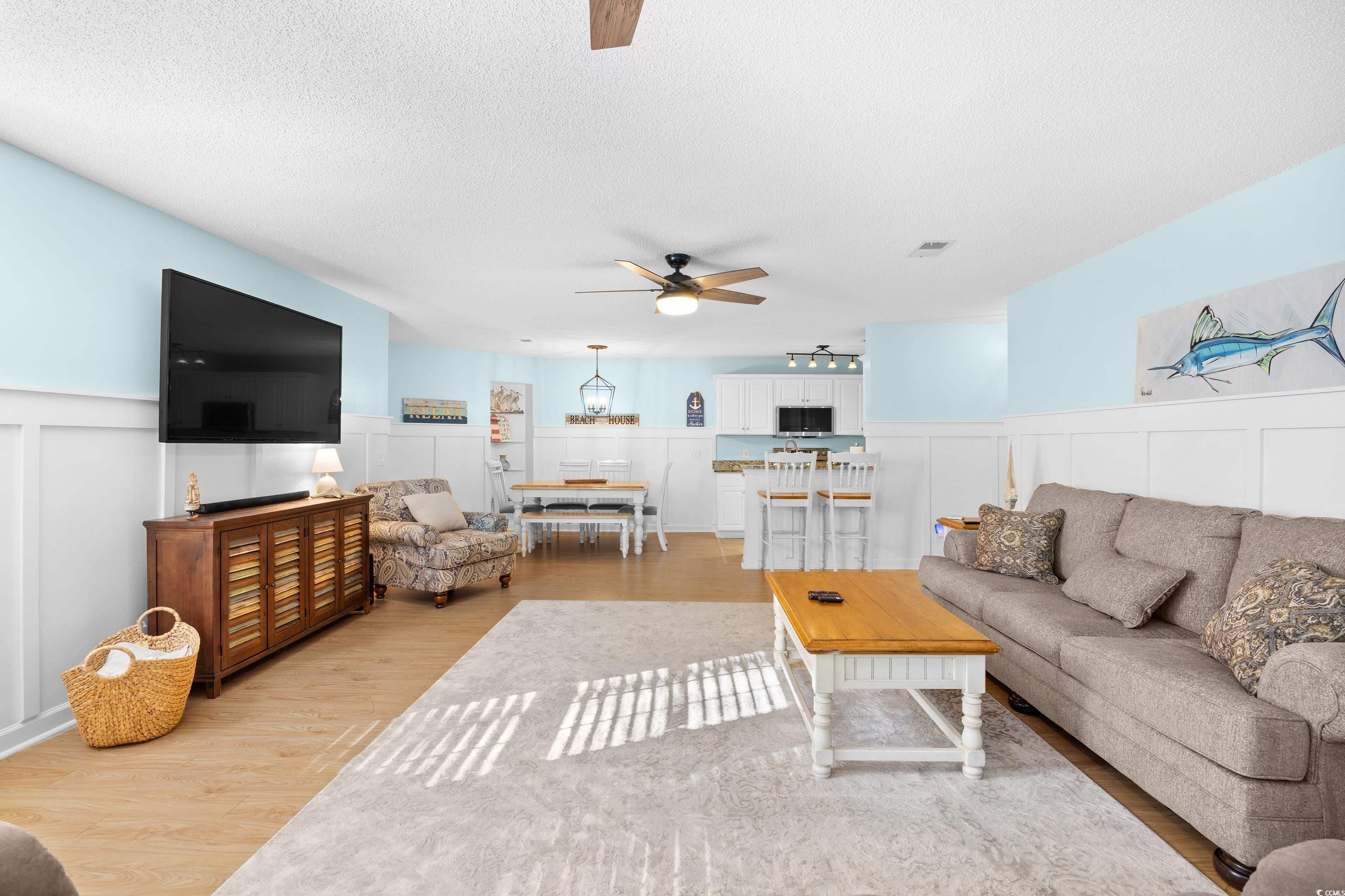 4277 Santolina Way, Unit D Murrells Inlet, SC 29576 - Photo 6 of 40 Living room featuring a decorative wall, wainscoting, a textured ceiling, light wood-type flooring, and ceiling fan