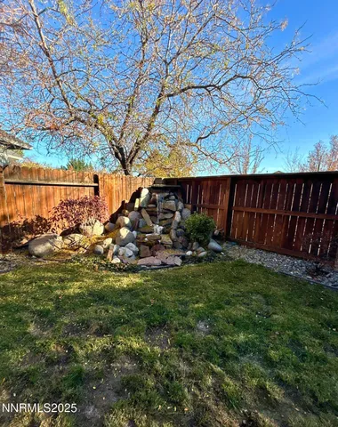a view of backyard with wooden fence and a large tree