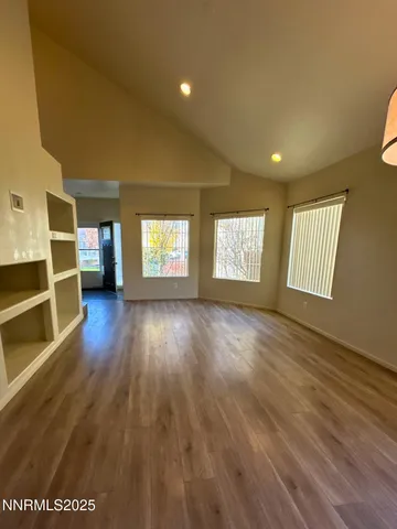 a view of an empty room with a window and wooden floor