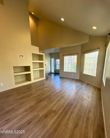 a view of an empty room with wooden floor and a window