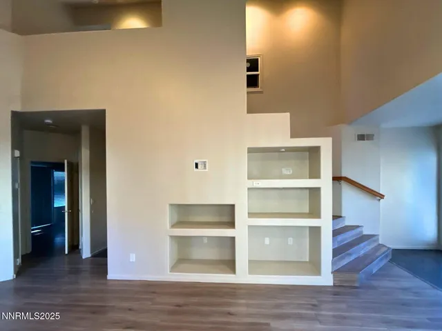 a view of an empty room with wooden floor and closet