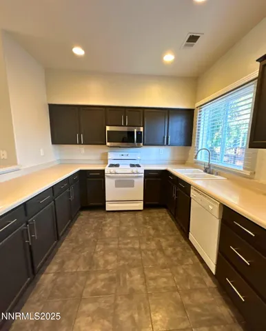 a kitchen with stainless steel appliances granite countertop a sink counter space cabinets and a large window