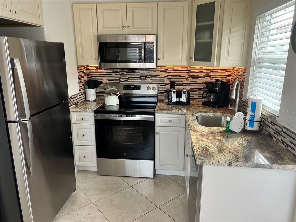 6154 Midnight Pass Road, Unit B07 Sarasota, FL 34242 - Photo 3 of 15 a kitchen with stainless steel appliances granite countertop a stove microwave and refrigerator