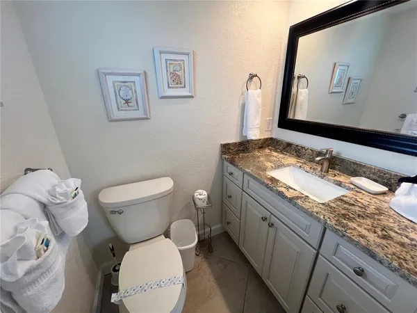 a bathroom with a granite countertop toilet sink and mirror