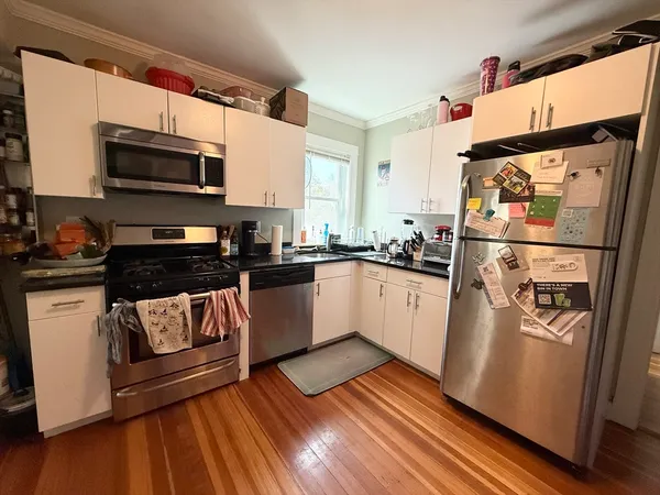 a white kitchen with stainless steel appliances granite countertop a stove a sink and a microwave