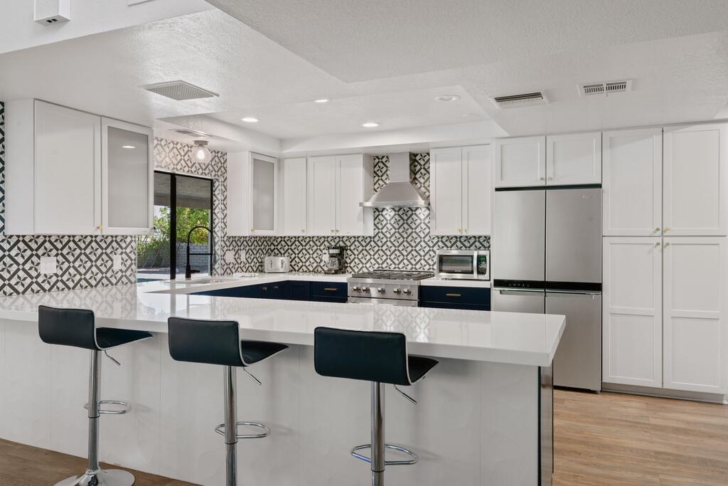 3060 East Verona Road Palm Springs, CA 92262 - Photo 8 of 33 a kitchen with stainless steel appliances kitchen island granite countertop a dining table chairs and white cabinets
