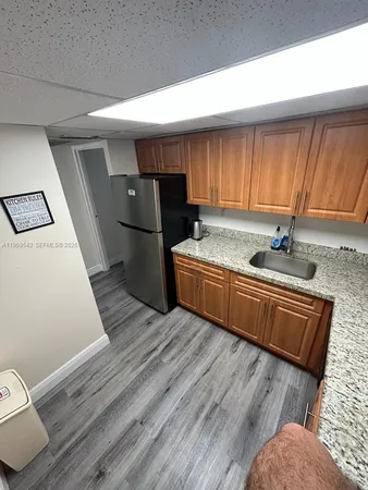 a kitchen with stainless steel appliances granite countertop a refrigerator a sink dishwasher a stove and white countertops with wooden floor