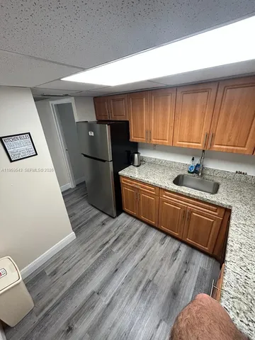 a kitchen with stainless steel appliances granite countertop a refrigerator a sink dishwasher a stove and white countertops with wooden floor