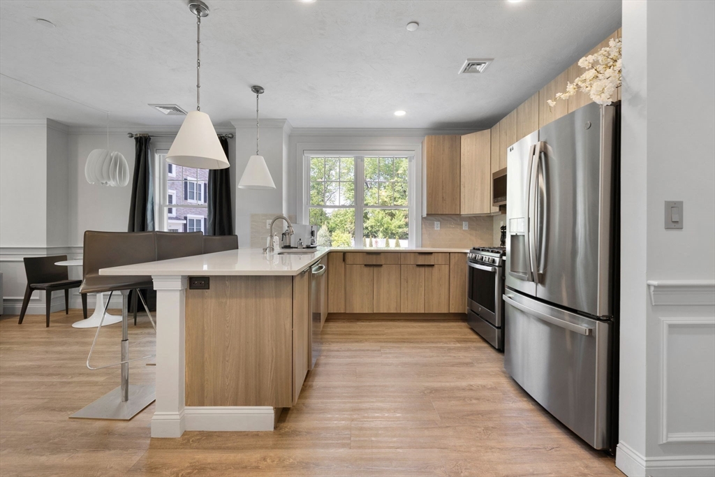 320 Middlesex Avenue, Unit B109 Medford, MA 02155 - Photo 2 of 21 a kitchen with stainless steel appliances granite countertop a refrigerator a sink dishwasher a stove and a dining table with wooden floor