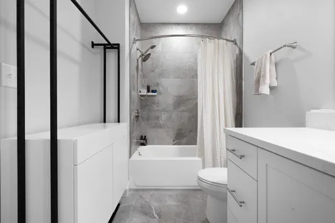 a bathroom with a bathtub shower sink vanity and toilet