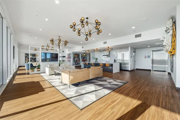 a living room with lots of furniture and kitchen view with wooden floor
