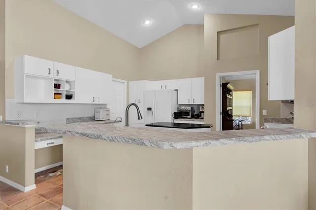 a kitchen with stainless steel appliances granite countertop a sink and white cabinets with wooden floor