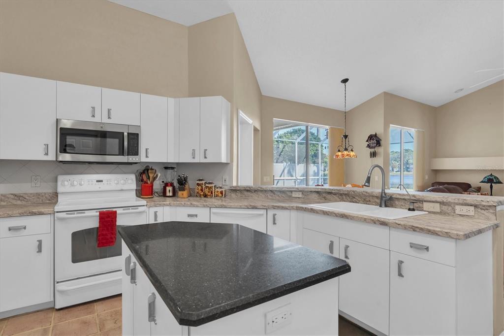1226 Hoversham Drive New Port Richey, FL 34655 - Photo 17 of 41 a kitchen with kitchen island granite countertop a sink a stove and cabinets