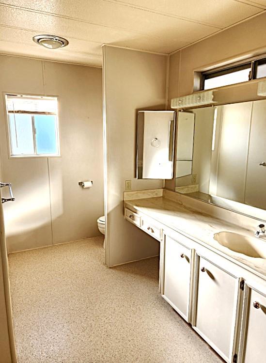 10113 Shamrock Lode Grass Valley, CA 95949 - Photo 27 of 34 a bathroom with a granite countertop sink a toilet and a shower
