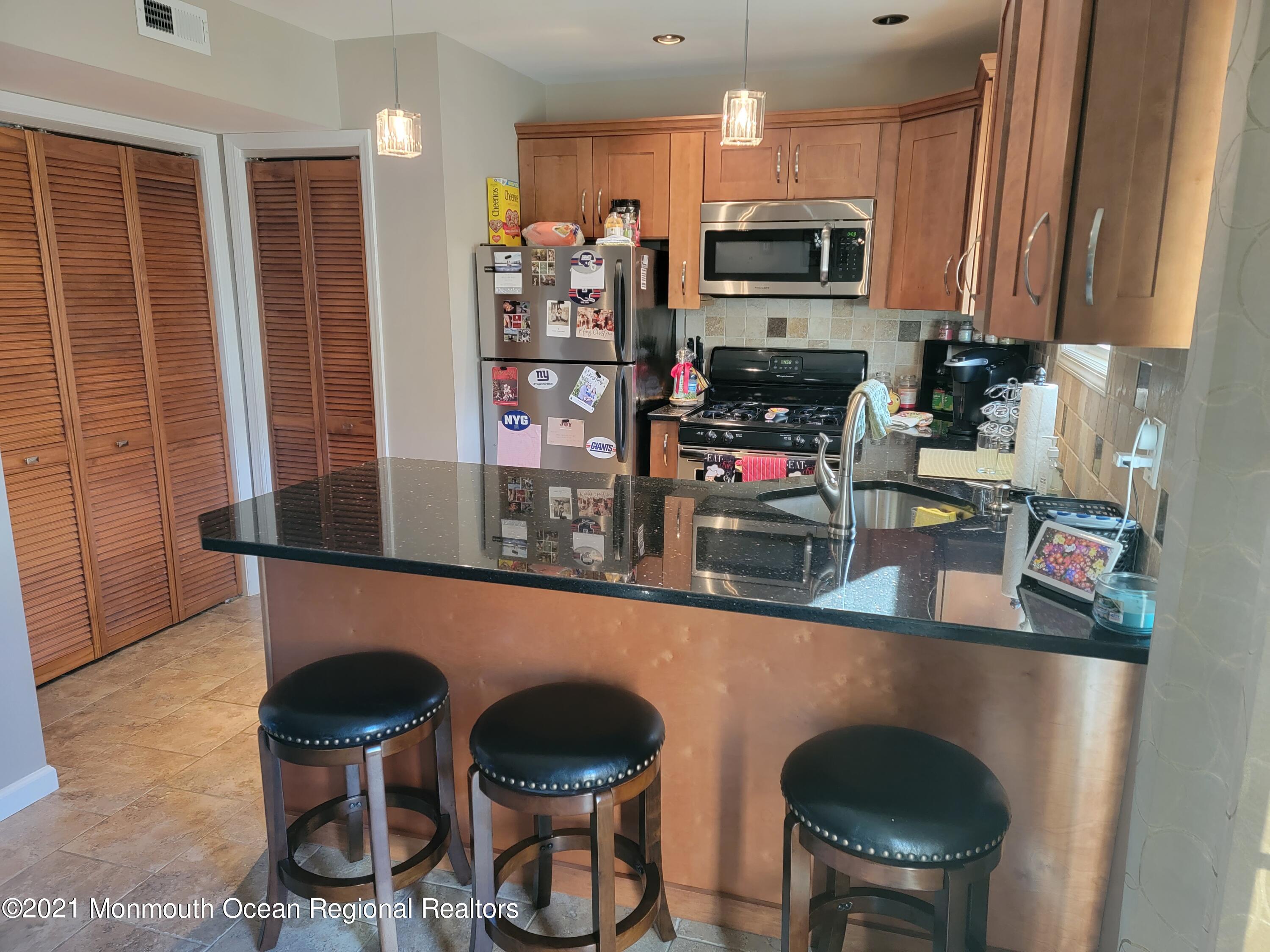 76 Greenwood Loop Road Brick, NJ 08724 - Photo 7 of 24 a kitchen with stainless steel appliances kitchen island granite countertop a table and chairs in it
