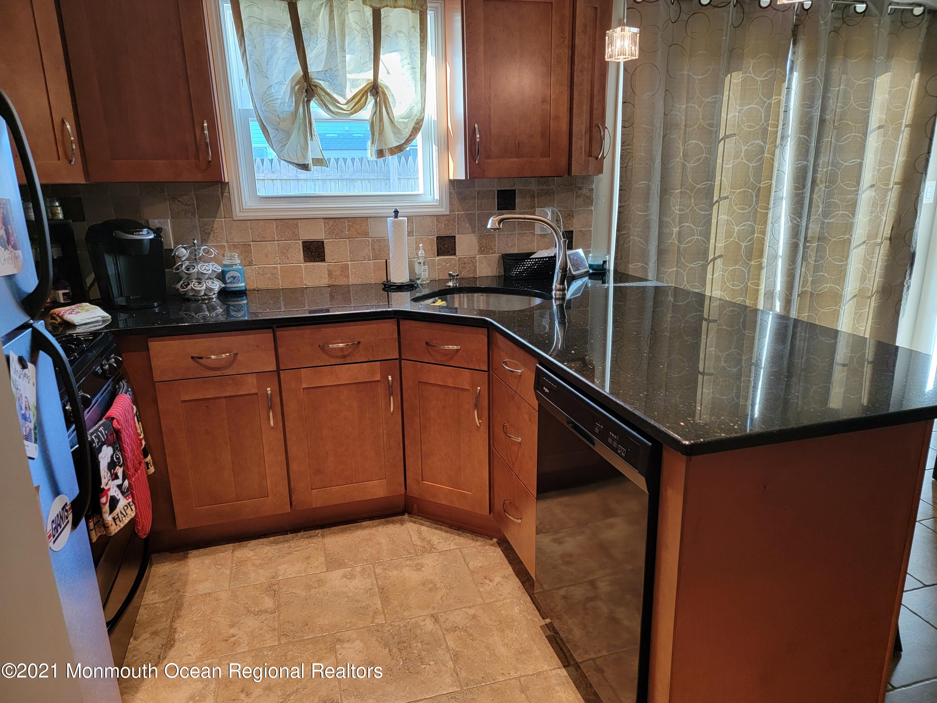 76 Greenwood Loop Road Brick, NJ 08724 - Photo 9 of 24 a kitchen with stainless steel appliances granite countertop a refrigerator a sink and wooden cabinets