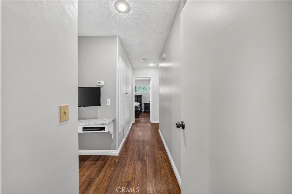 29078 Bradley Road Menifee, CA 92586 - Photo 20 of 42 a view of a hallway with wooden floor and a flat screen tv