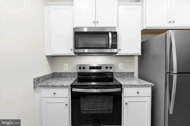 a kitchen with stainless steel appliances granite countertop a sink a refrigerator and a granite counter tops