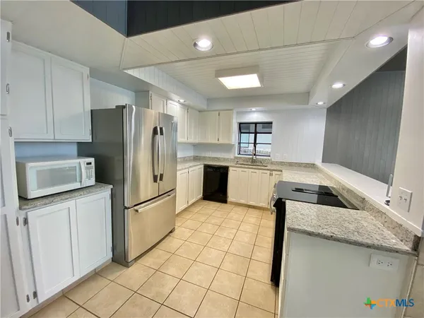 a kitchen with stainless steel appliances granite countertop a refrigerator a sink and a stove