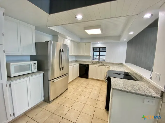 a kitchen with stainless steel appliances granite countertop a refrigerator a sink and a stove