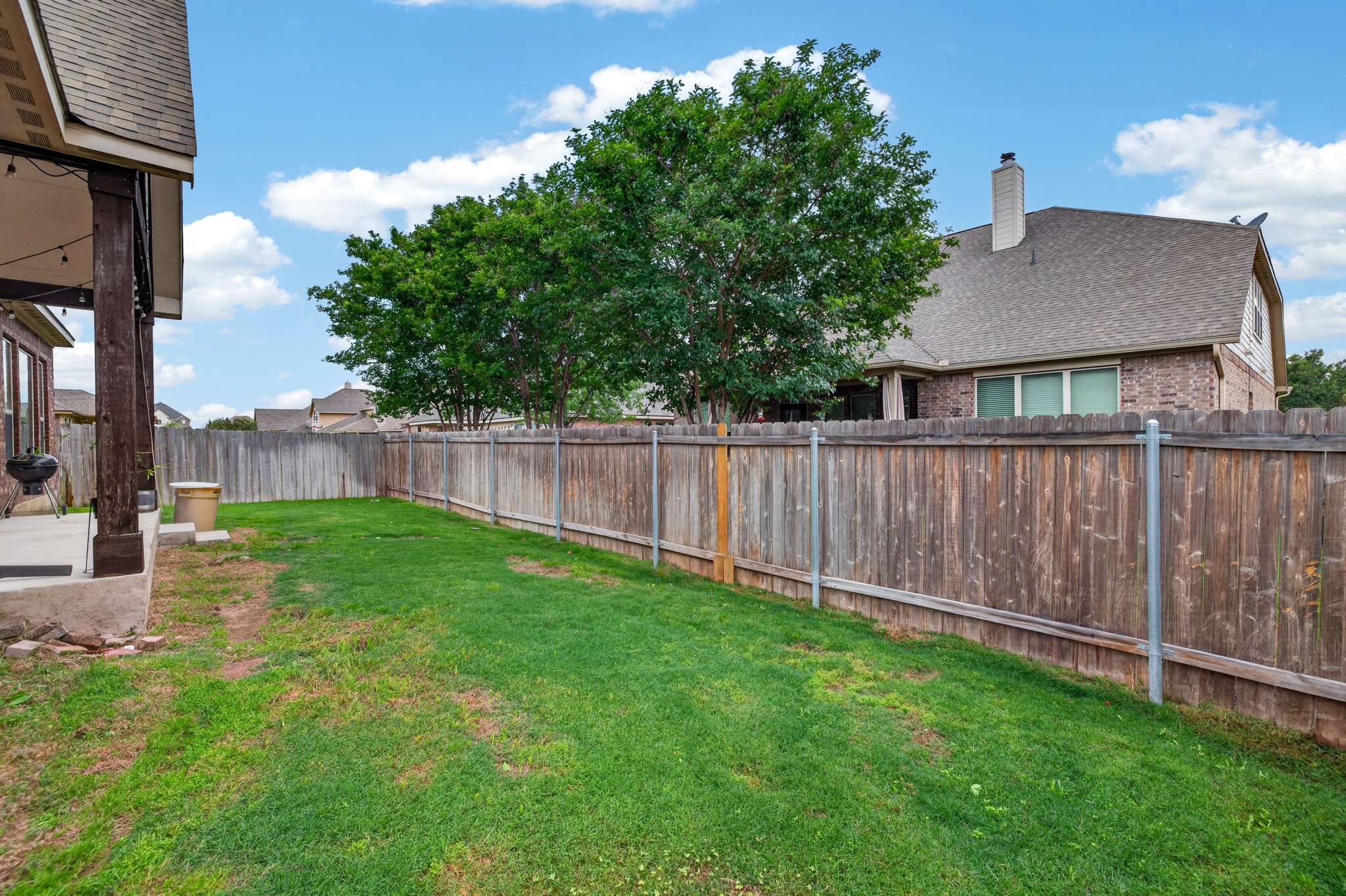1017 Tabernash Leander, TX 78641 - Photo 37 of 38 Expansive backyard featuring a lush lawn, privacy fencing, mature trees, and a covered patio with string lighting