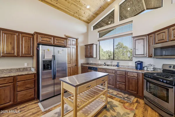 a kitchen with stainless steel appliances granite countertop a stove top oven a sink dishwasher a refrigerator and cabinets with wooden floor