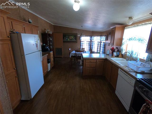 609 3rd Avenue Romeo, CO 81148 - Photo 4 of 16 Kitchen with vaulted ceiling, sink, dark hardwood / wood-style floors, white appliances, and kitchen peninsula