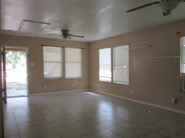an empty room with windows and chandelier fan