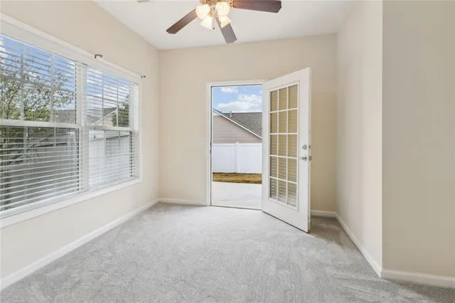 an empty room with a windows and chandelier fan