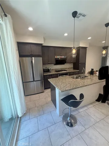 a view of kitchen with stainless steel appliances granite countertop a sink and a refrigerator