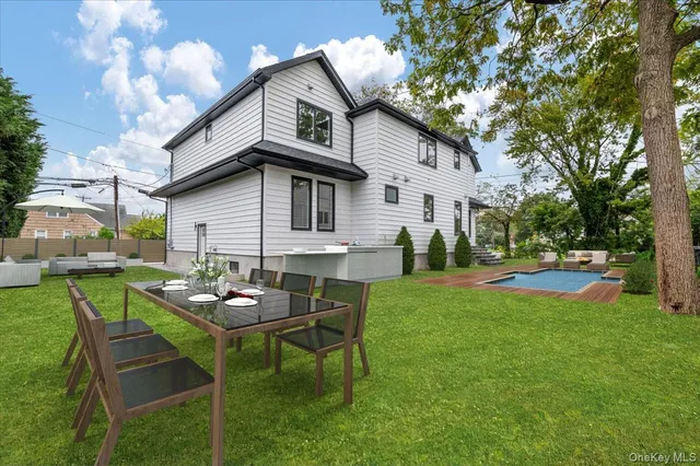 a view of a white house with a big yard couches and table and chairs