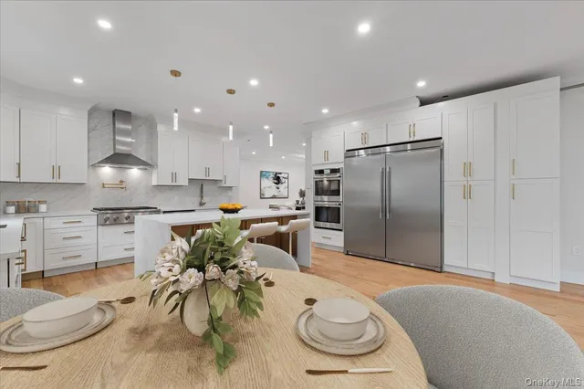 a kitchen with stainless steel appliances kitchen island granite countertop a refrigerator a stove a oven a sink with a dining table and chairs