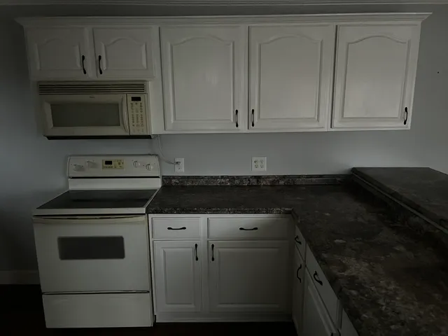 a kitchen with white cabinets and black appliances