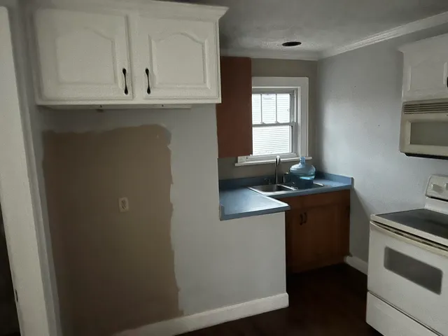 a kitchen with granite countertop white cabinets and black appliances