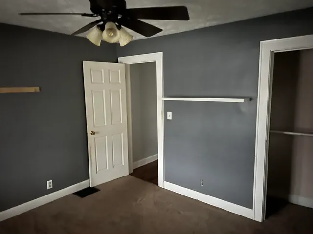an empty room with closet and a chandelier fan