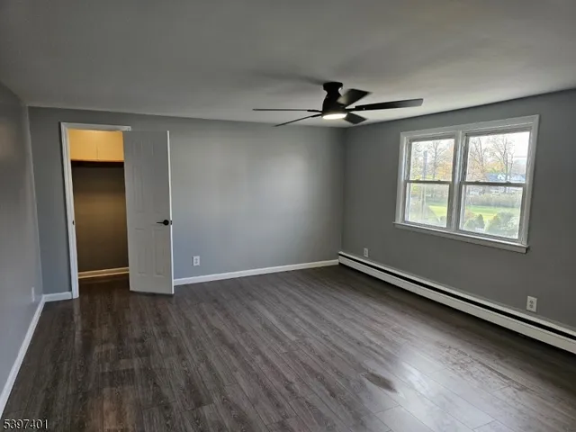 an empty room with wooden floor ceiling fan and windows