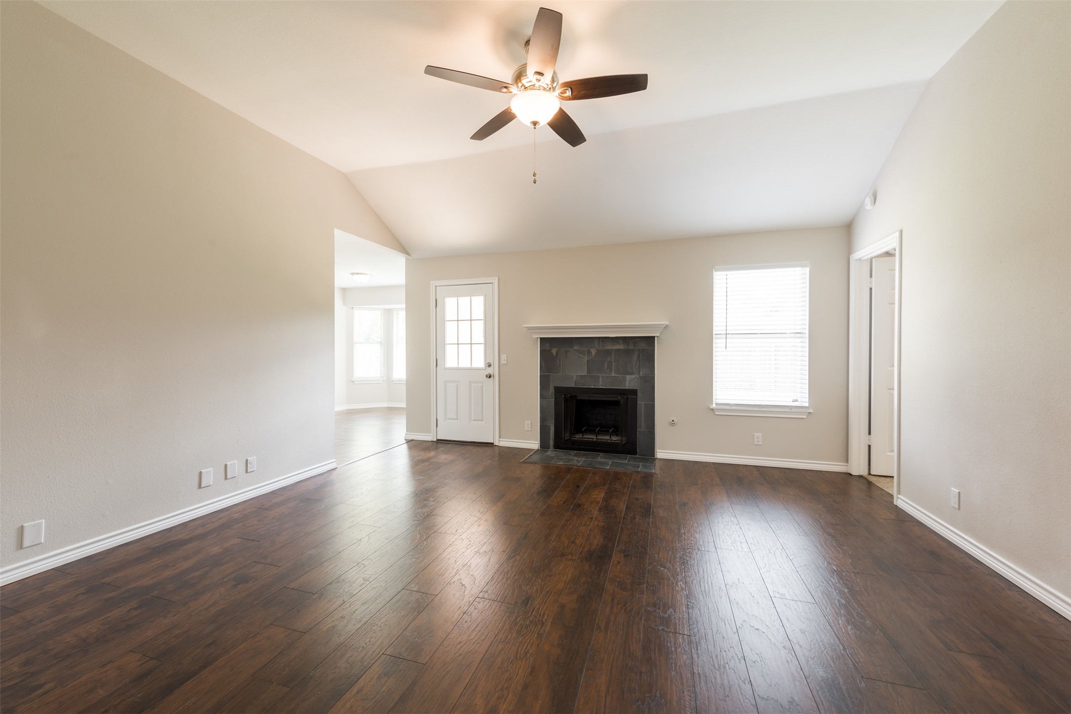 5703 Teri Road Austin, TX 78744 - Photo 3 of 16 an empty room with wooden floor fireplace and windows