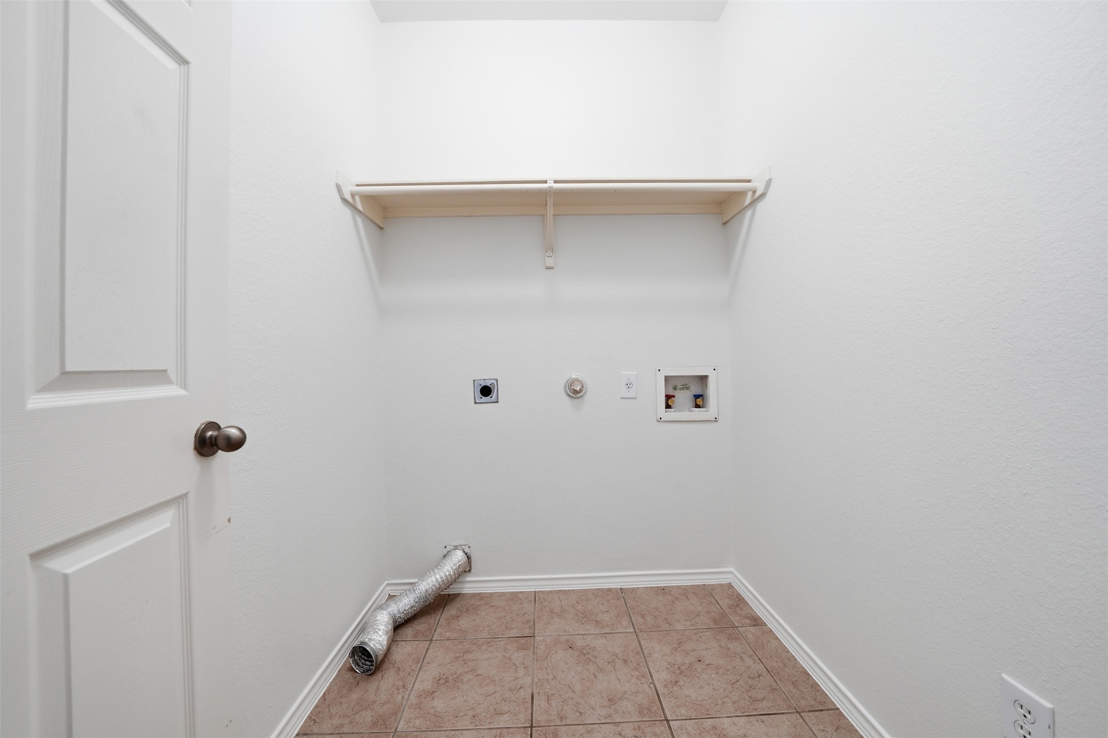 118 Invierno Street Kyle, TX 78640 - Photo 31 of 37 A dedicated laundry space provides practical utility with tile flooring and a convenient storage shelf.