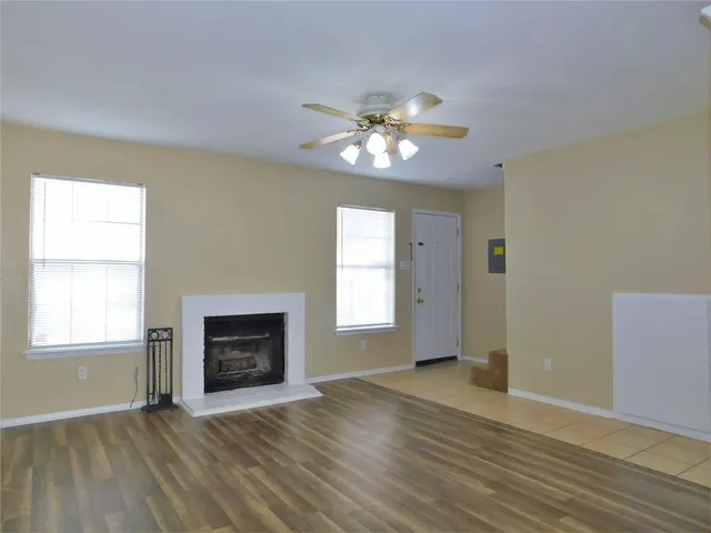 an empty room with windows chandelier and fireplace