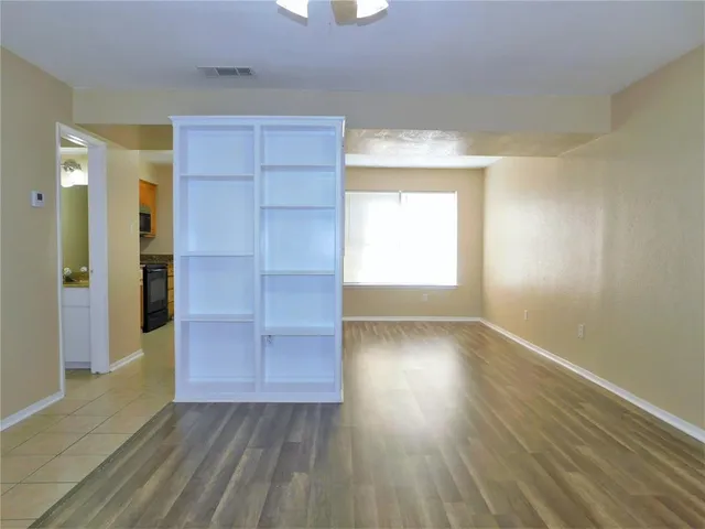 an empty room with wooden floor closet and windows