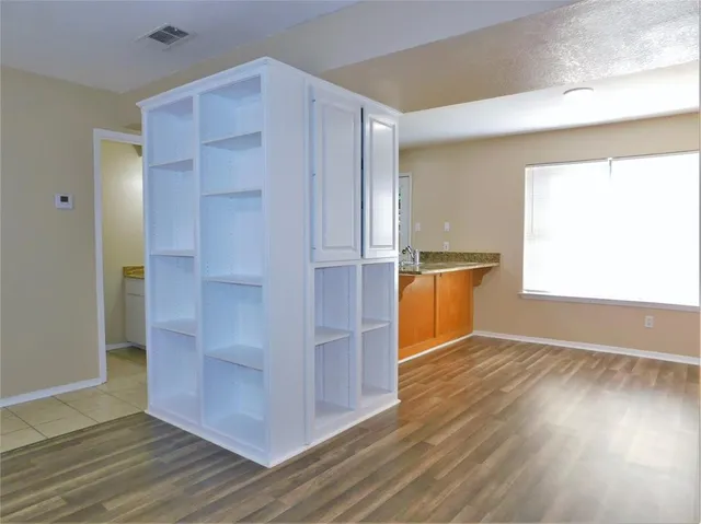 an empty room with wooden floor cabinet and windows
