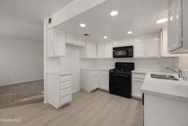 a kitchen with granite countertop white cabinets and stainless steel appliances