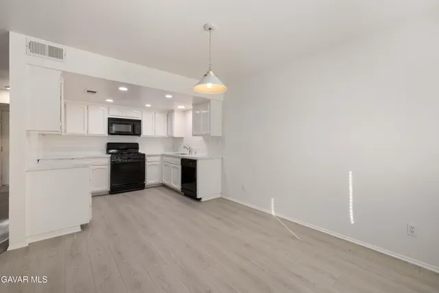a view of a kitchen with a sink wooden cabinets and a window