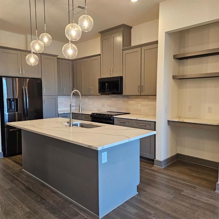 2700 Old Denton Road, Unit 2238 Carrollton, TX 75007 - Photo 10 of 21 Kitchen featuring a center island with sink, white countertops, gray cabinetry, and a full suite of black kitchen appliances